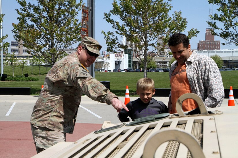 Major Harold Aprill, the executive officer for the 3rd Battalion, 399th Regiment, shows a young boy and his father the durability of a Humvee during the 2016 Armed Forces Day celebration at the Milwaukee Harley-Davidson Museum, May 21, 2016.  Aprill, who is also a member of the Milwaukee Armed Services Committee, helped organize the event which capped off an entire week of activities for Milwaukee's Armed Forces Week.   Aprill and reservists from the 3/399th, as well as volunteers from the other branches, helped raise military awareness by displaying military vehicles and explaining to civilians their current role in supporting ongoing military efforts around the world. Service members past and present mingled with the crowd throughout the day, a highlight of which was the 13th annual Support the Troops Ride which featured over 300 motorcycle riders.