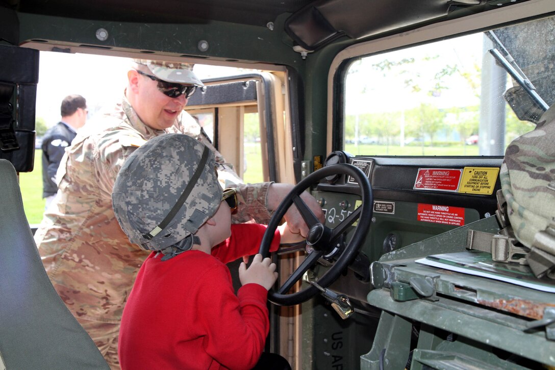 Major Harold Aprill, the executive officer for the 3rd Battalion, 399th Regiment, shows Max Osmak of St. Francis, Wis. how to start a Humvee during the 2016 Armed Forces Day celebration at the Milwaukee Harley-Davidson Museum, May 21, 2016.  Aprill, who is also a member of the Milwaukee Armed Services Committee, helped organize the event which capped off an entire week of activities for Milwaukee's Armed Forces Week.   Aprill and reservists from the 3/399th, as well as volunteers from the other branches, helped raise military awareness by displaying military vehicles and explaining to civilians their current role in supporting ongoing military efforts around the world. Service members past and present mingled with the crowd throughout the day, a highlight of which was the 13th annual Support the Troops Ride which featured over 300 motorcycle riders.