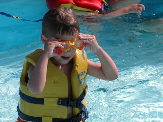 A child adjusts his swim goggles while wearing a life jacket at the Barksdale Air Force Base, La., pool. Children 15 and under must wear a life jacket until they demonstrate their ability to swim during a swim test. (Courtesy photo)