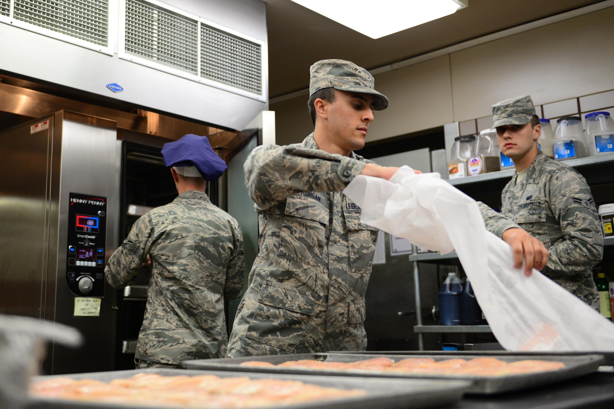 U.S. Air Force Airman Tyler Morgan, a 354th Force Support Squadron food service apprentice, takes paper off chicken May 31, 2016, at Eielson Air Force Base, Alaska. Morgan is preparing to season chicken for chicken parmesan. (U.S. Air Force photo by Airman 1st Class Cassandra Whitman/Released)