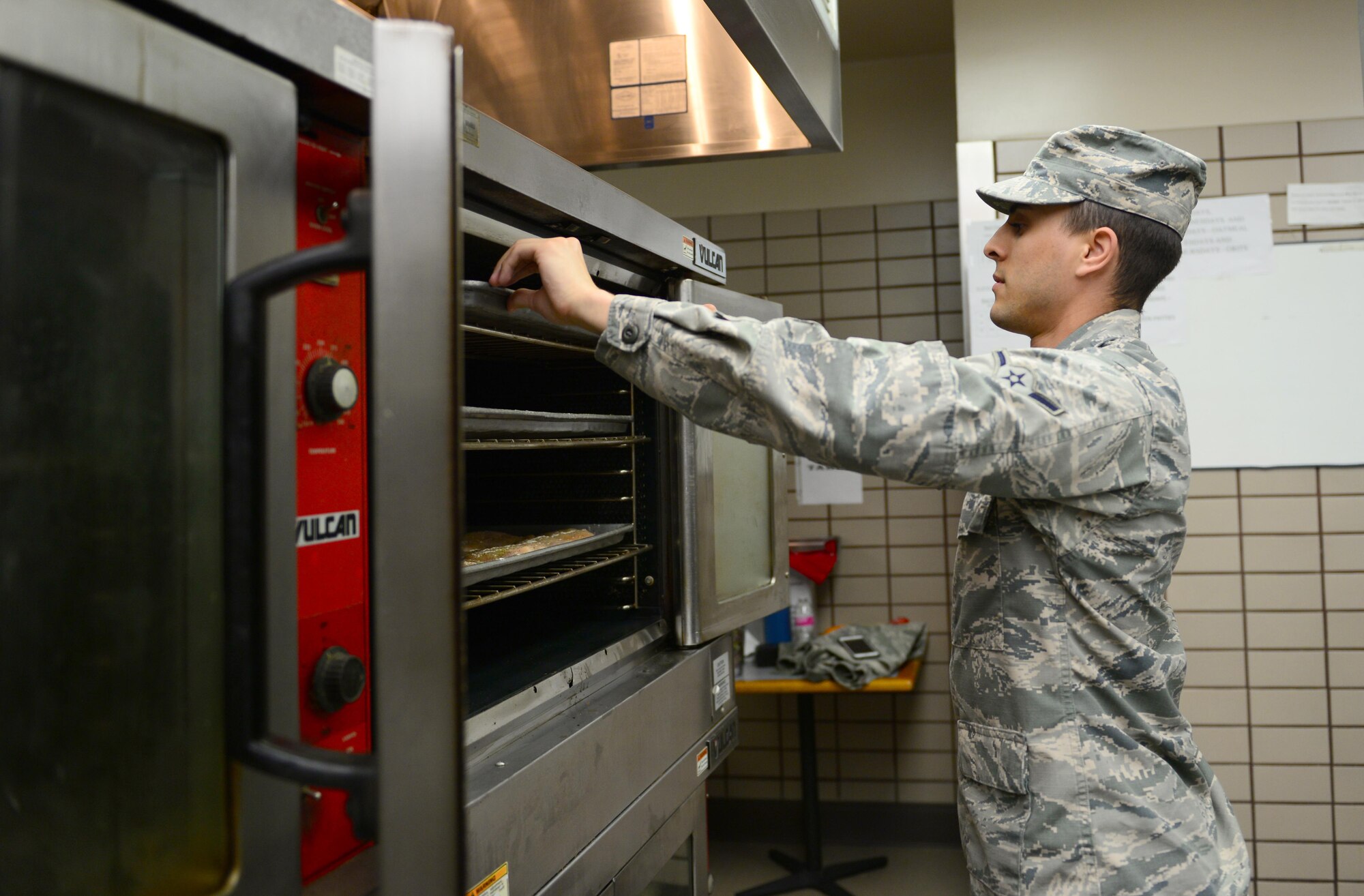 U.S. Air Force Airman Tyler Morgan, a 354th Force Support Squadron food service apprentice, puts a pan of chicken in the oven May 31, 2016, at Eielson Air Force Base, Alaska. Morgan finished putting spices on chicken and placed the pans in the ovens to cook for lunch. (U.S. Air Force photo by Airman 1st Class Cassandra Whitman/Released)