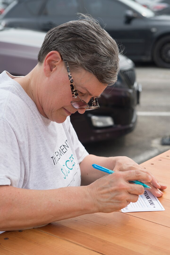 Retired Army Sgt. Maj. Cheryl Faimon writes a letter to military members for their service during Sunny Anderson’s visit to Joint Base San Antonio-Lackland May 25. During the visit, Anderson, Food Network host and chef, signed autographs and gave free copies of her new book, “Sunny’s Kitchen,” to guests as part of a cross-country tour with Operation Gratitude, which has sent about 1.5 million care packages to service members.