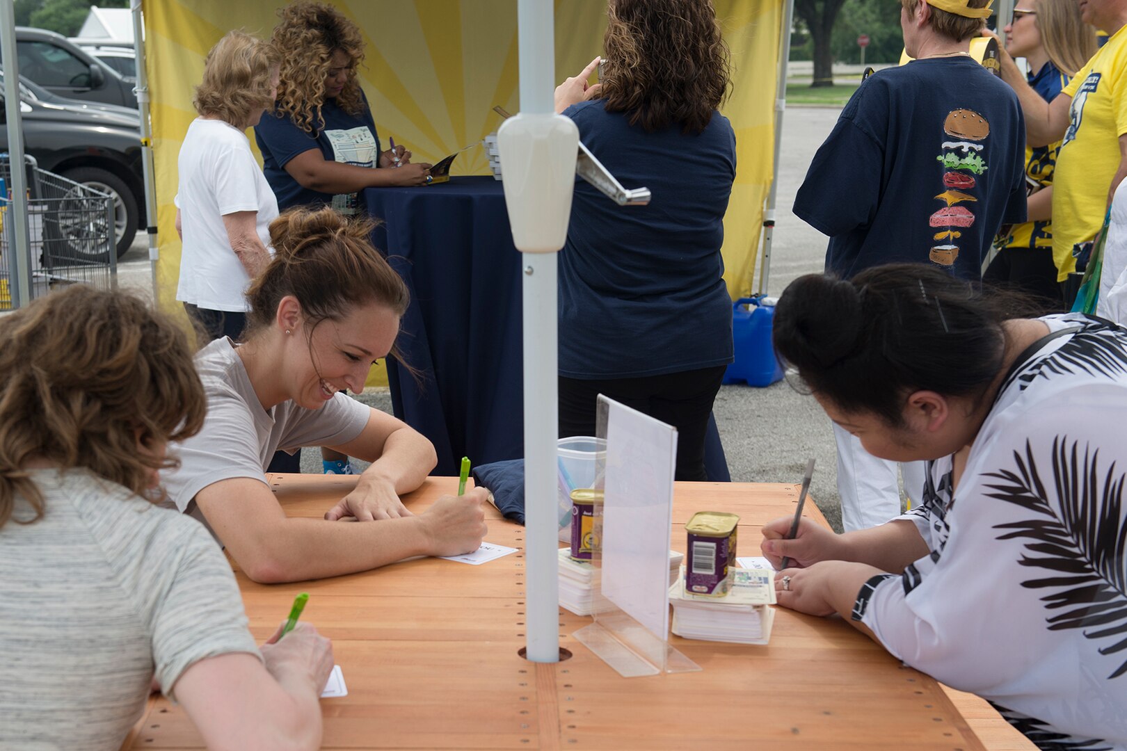 (From left to right) Stephanie McGuane, Burson Marsteller public relations manager; Ashley Hillig, Match Marking Group account manager; and Jenna Greenwell, military spouse, write thank you letters to service members during Sunny Anderson’s visit to Joint Base San Antonio-Lackland May 25. During the visit, Anderson, Food Network host and chef, signed autographs and gave free copies of her new book, “Sunny’s Kitchen,” to guests as part of a cross-country tour with Operation Gratitude, which has sent about 1.5 million care packages to service members.