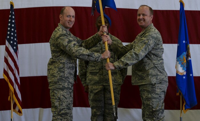 Col. Jason Hinds, 57th Wing vice commander, assumes command from Col. Mark Rose during the 57th Maintenance Group change of command ceremony held in Lightning Aircraft Maintenance Unit hangar at Nellis Air Force Base, Nev., May 26, 2016. This unique group honored its commander of three years during the ceremony, taking time to highlight the accomplishments of the 57th MXG while lead by Rose. (U.S. Air Force photo by Airman 1st Class Kevin Tanenbaum)
