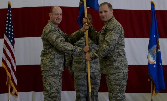 Col. Shane Henderson assumes command from Col. Jason Hinds, 57th Wing vice commander, during the change of command ceremony held in Lightning Aircraft Maintenance Unit hangar at Nellis Air Force Base, Nev., May 26, 2016. The mission critical task of supporting 10 flying programs and 120 assigned A-10, F-15, F-16, F-22A and F-35 aircraft as well as all visiting Red Flag, Green Flag, and operational test and evaluation aircraft is a vital one that the 57th Maintenance Group accomplishes day in and day out. (U.S. Air Force photo by Airman 1st Class Kevin Tanenbaum)