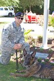 U.S. Air Force Staff Sergeant Jonathan Garrett, Military Working Dog handler, 628th Security Forces Squadron, poses with military working dog Chico in front of the Joan August Terry military memorial on May 20, 2016, at the Charleston Animal Society campus, S.C. The Terry military memorial commemorates the military service of men, women and the animals that served alongside them. (Courtesy photo by Charleston Animal Society)