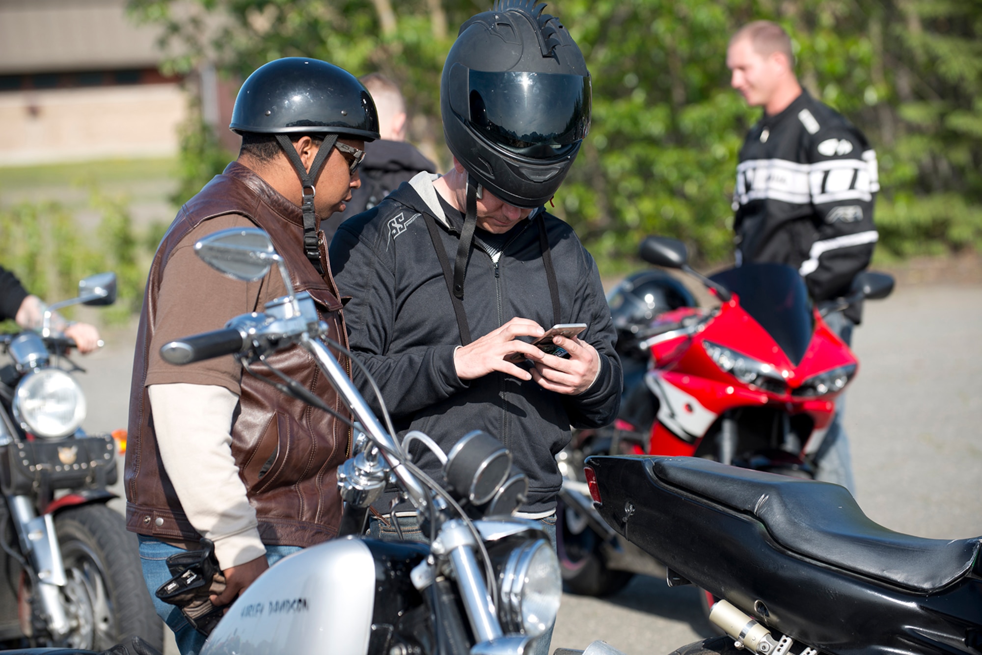 Riders share stories and photos at the motorcycle safety pad on JBER-Richardson, May 26. The Joint Base Elmendorf-Richardson annual motorcycle safety ride is designed to connect new riders with experienced riders to foster mentor relationships and hone their skills together. (U.S. Air Force photo by Senior Airman Kyle Johnson)