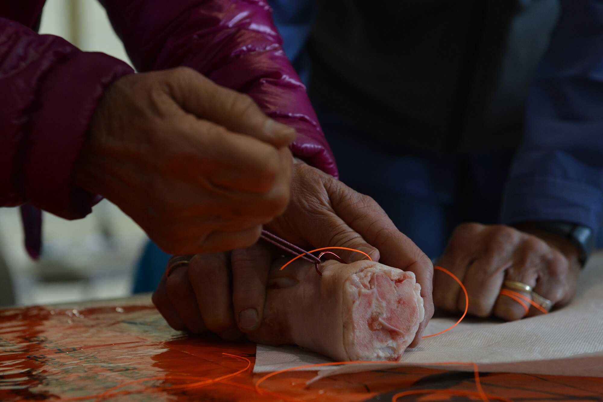 Vendors demonstrate a method to properly remove a fish hook accidentally lodged under ones skin at the safety fair in Hangar 1 on Joint Base Elmendorf-Richardson, Alaska, May 26, 2016. Avalanche, boating, hunting and fishing, firearm and bicycle safety were among the recreational safety topics covered at the event. (U.S. Air Force photo by Airman 1st Class Javier Alvarez)