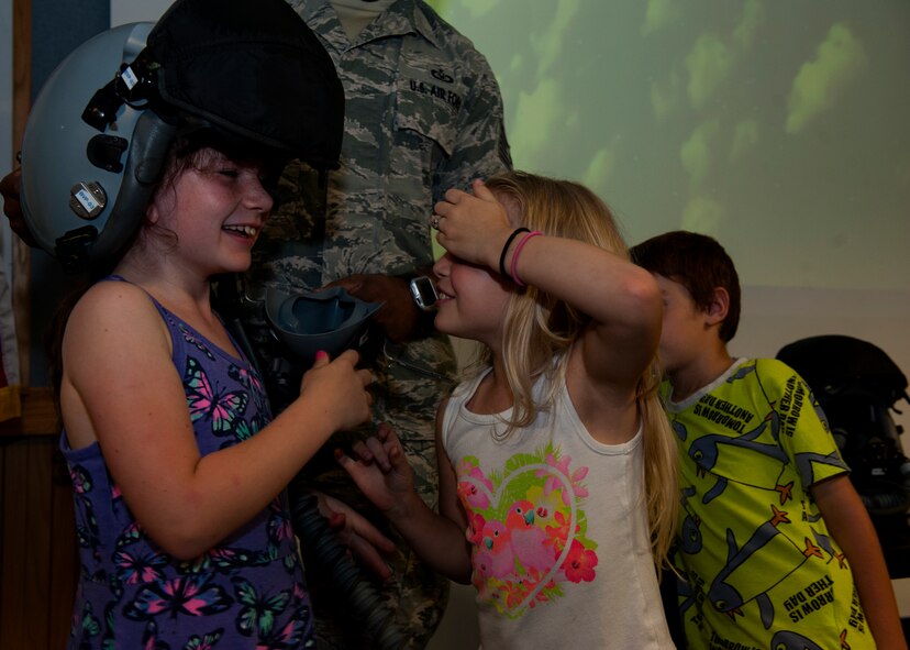 Addison Smith, Brooklyn Davis and Alex Rinaldi, Bechtel elementary first grade students, interact with helmets used by F-15 Eagle fighter pilots during a career day May 16, 2016, at Kadena Air Base, Japan. Bechtel Elementary is located on Camp McTureous, near Uruma. (U.S. Air Force photo by Airman 1st Class Lynette M. Rolen)