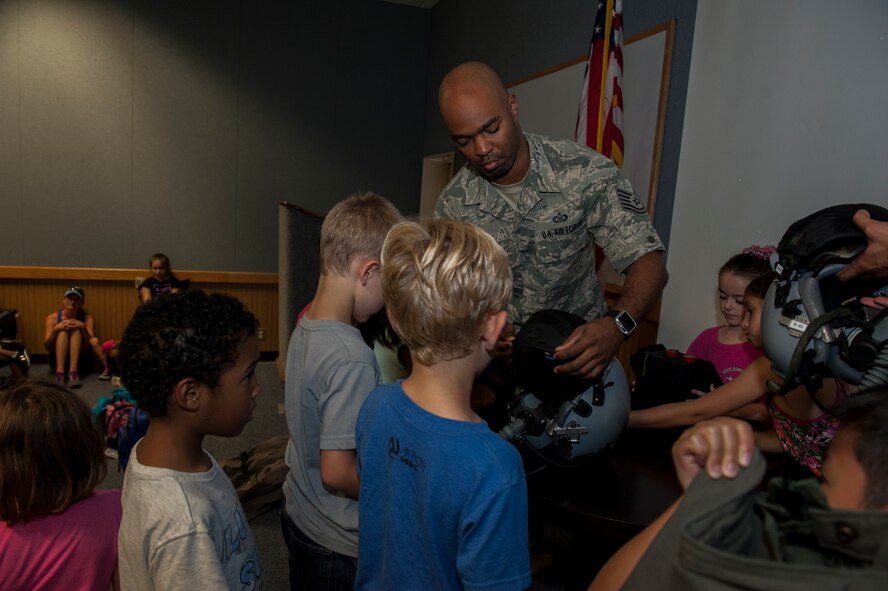 U.S. Air Force Tech. Sgt. Christopher Wilson, 44th Fighter Squadron Aircrew Flight Equipment NCOIC, interacts with first grade students from Bechtel Elementary School as he shows off aircrew flight equipment May 16, 2016, at Kadena Air Base, Japan. One piece of equipment was a helmet that 44th Fighter Squadron pilots use. In addition to the helmet, students also saw night vision goggles. (U.S. Air Force photo by Airman 1st Class Lynette M. Rolen)