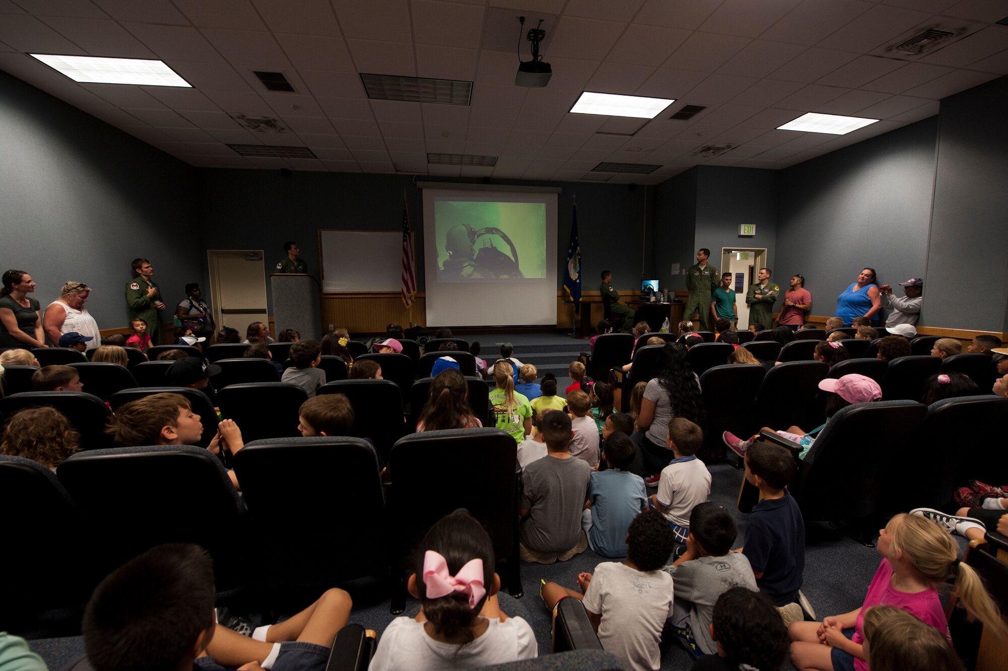 First grade students from Bechtel Elementary School watch a video about fighter jets and pilots May 16, 2016, at Kadena Air Base, Japan. The students were invited to Kadena to receive a mission briefing by the 44th Fighter Squadron, an F-15 Eagle tour and learn about aircrew flight equipment. More than 100 students attended the event. (U.S. Air Force photo by Airman 1st Class Lynette M. Rolen)