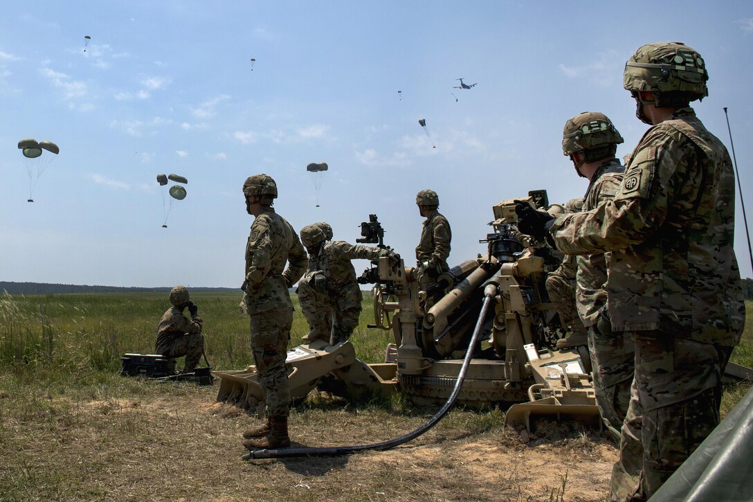 Soldiers watch as an Air Force Globemaster III aircrafts drops equipment over the drop zone during exercise Crescent Reach at Fort Bragg, N.C., May 26, 2016. The soldiers are assigned to the 82nd Airborne Division’s 3rd Battalion, 319th Airborne Field Artillery Regiment. Air Force photo by Airman 1st Class Sean Carnes