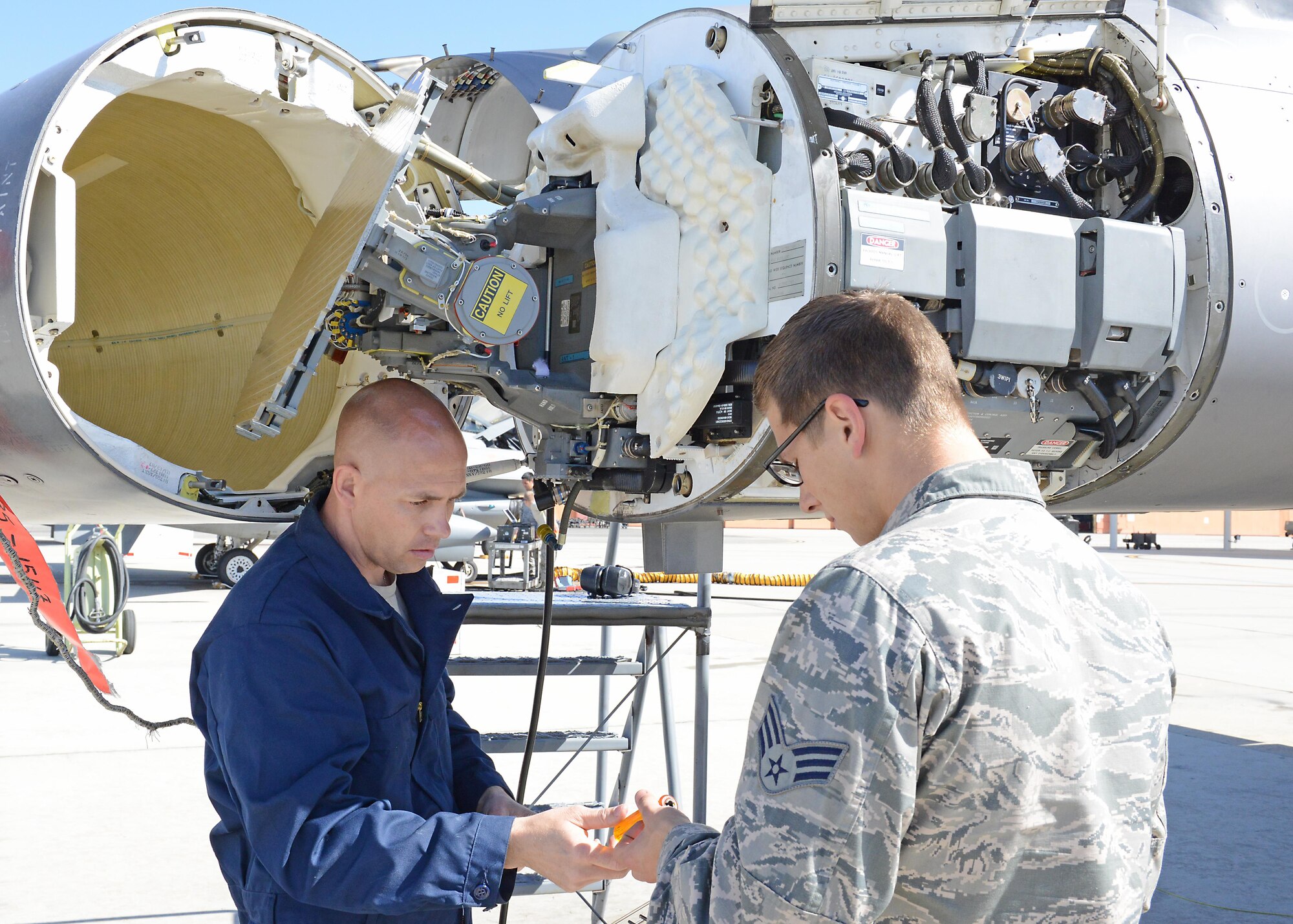 Senior Master Sgt. Samuel Rock, an Air Force Reserve volunteer from Seymour Johnson Air Force Base, N.C., works with Senior Airman Quilan Johansen, of the 412th Aircraft Maintenance Squadron, on an F-16 Fighting Falcon radar waveguide pressurization. Reservists are augmenting F-16 support for KC-46 Pegasus testing at Edwards Air Force Base, Calif. (U.S. Air force photo/Kenji Thuloweit)