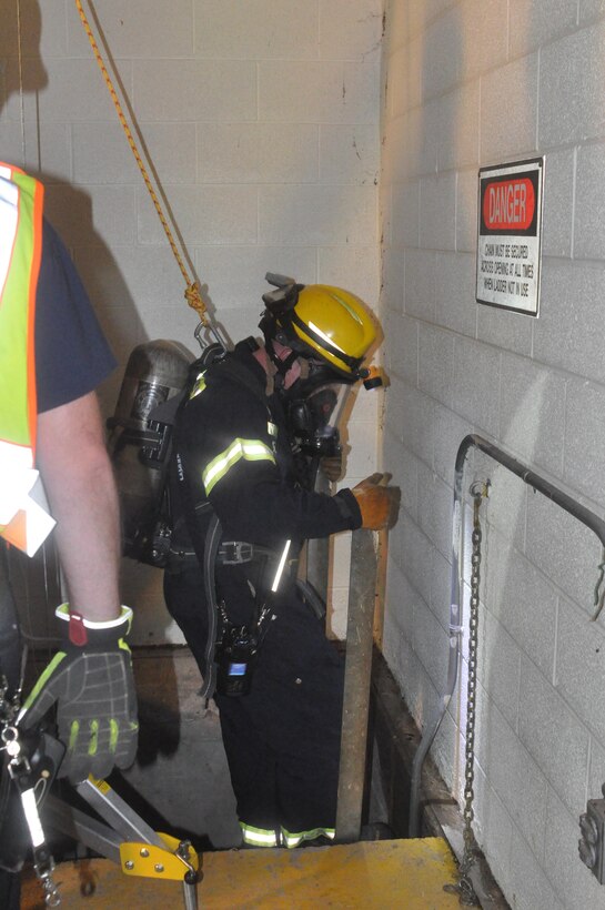 Rescuers enter a confined space in the floor in order to rescue a victim that fell off the ladder during a simulated medical emergency.