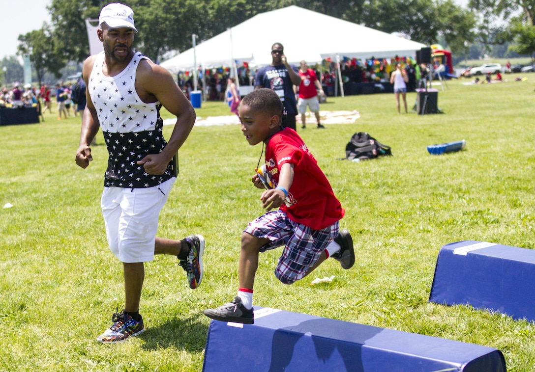 Former Washington Redskins wide receiver Antwaan Randle El runs football drills with a child during the Playfield in the Park in Washington, D.C., on May 28. Playfield in the Park partnered with Tragedy Assistance Program for Survivors to give the kids a day in the park to have fun. (U.S. Army photo by Spc. Victoria Friend)