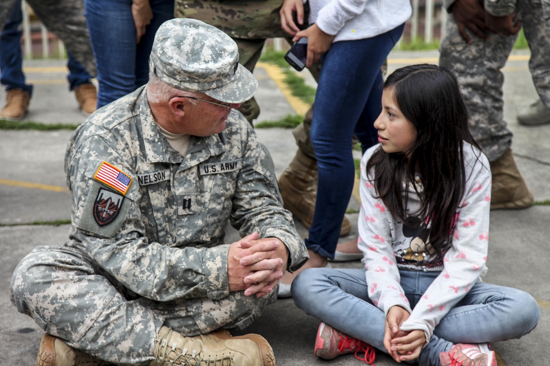 Army Capt. Saint Nelson sits on the ground to speak with a Guatemalan student in San Marcos, Guatemala, June 1, 2016. Task Force Red Wolf and Army South conduct Humanitarian Civil Assistance Training, which includes construction projects, building schools and medical readiness training. Nelson is assigned to the 345th Psychological Operations Company Airborne. Army photo by Spc. Tamara Cummings