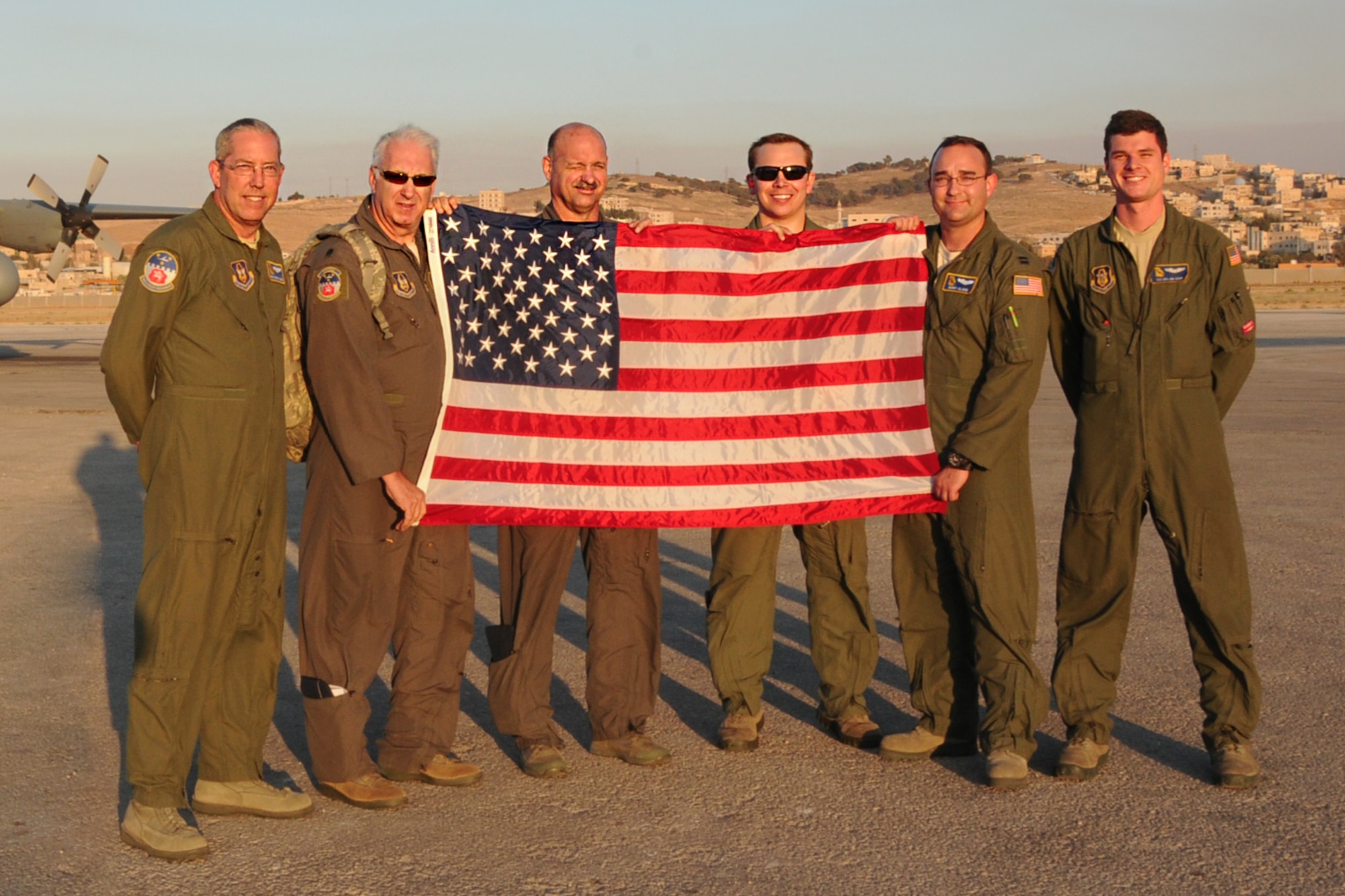 700th Airlift Squadron aircrew members display an American flag that flew on their C-130 flight over Jordan in support of Exercise Eager Lion, May 19, 2016. This year, Eager Lion was a bilateral exercise including the U.S. and Jordanian military forces. (U.S. Air Force photo/Staff Sgt. Alan Abernethy)
