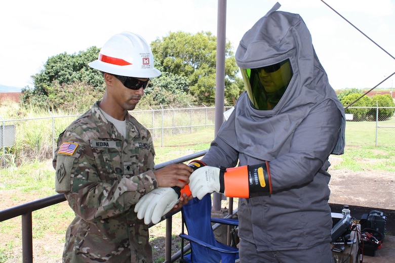 HELEMANO MILITARY RESERVATION (May 24, 2016) -- Electrician Jonathan Medina assists Power Station Mechanic Sgt. Jonathan Craft don an electrical protection suit prior to opening energized power panels inside the Helemano power substation. 