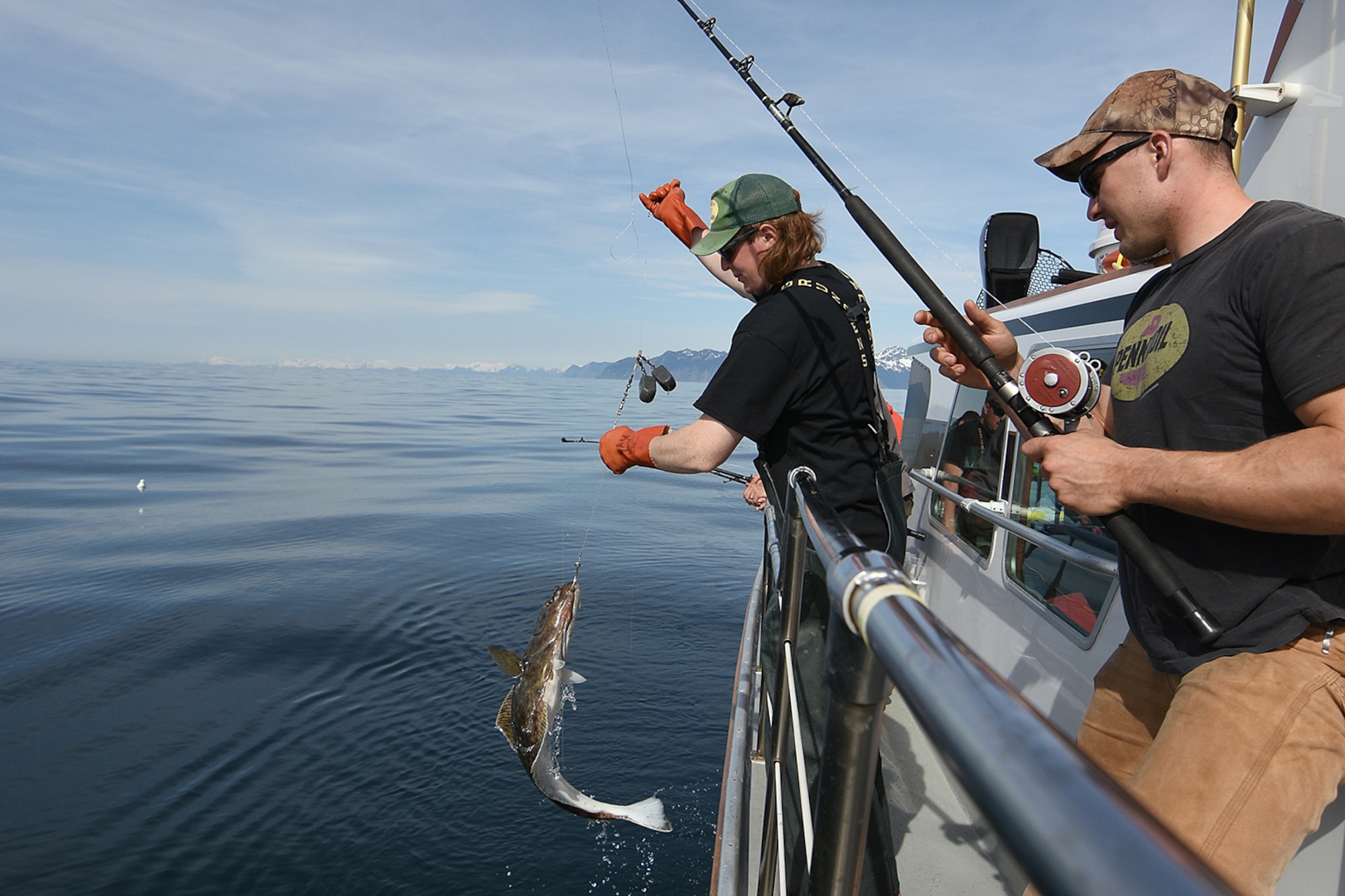 Volunteer deck hand Kyle Collins lands a small halibut for Air Force Staff Sgt. Parker Dalla in the 10th Annual Armed Services Combat Fishing Tournament May 26 aboard the Seward Military Resort boat, Snowbird. The tournament, hosted by the city of Seward and the Armed Services YMCA, gave more than 200 military anglers stationed in Alaska a free day of halibut fishing to thank them for their service. (U.S. Army photo by John Pennell)