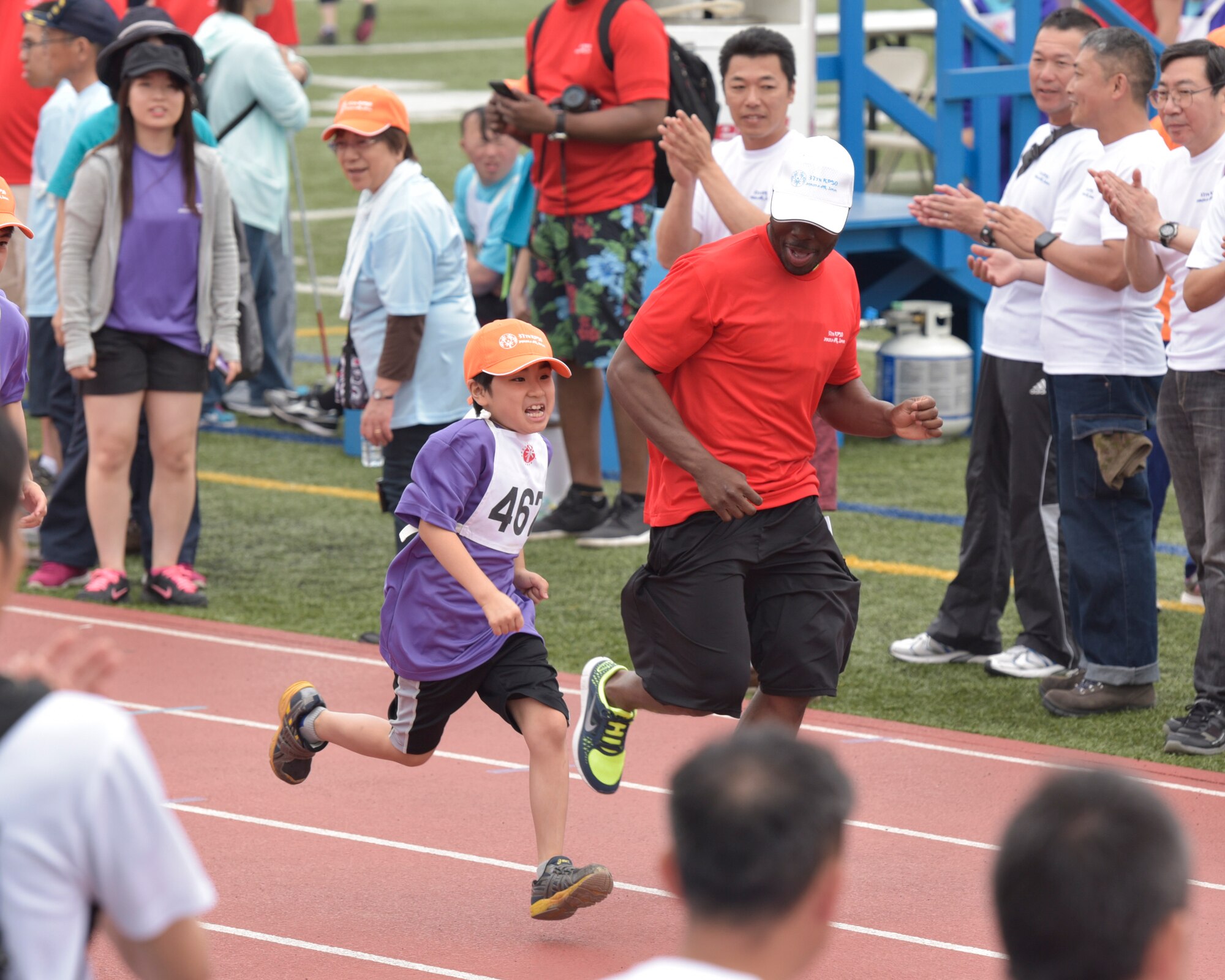 An athlete runs alongside a volunteer in the 50-meter sprint during the 37th Annual Kanto Plains Special Olympics held at Yokota Air Base, Japan, May 28, 2016. Each athlete was assigned a buddy, or a volunteer, to escort, keep company with, and cheer on their athlete throughout the event. (U.S. Air Force photo by Machiko Imai/Released)