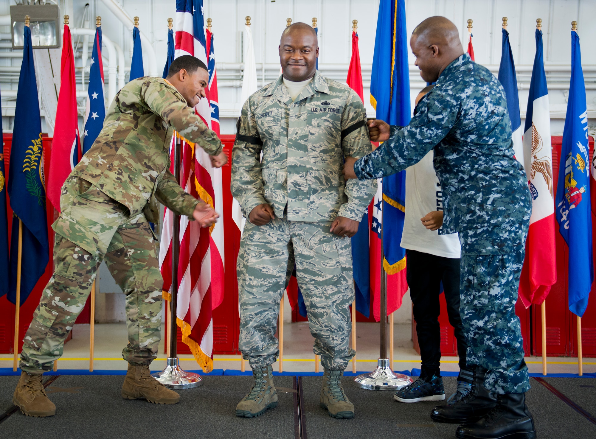 Master Sgt. Antone Scott, 96th Maintenance Group, has his new stripe “tacked” on by his son, Spc. Teyvon Scott, and his twin brother, Lt. Cmdr. Anthony Scott, during his promotion ceremony May 31 at Eglin Air Force Base, Fla.  Antone’s brother administered the oath of enlistment to the new senior master sergeant earlier in the day to meet the requirements for the promotion.  (U.S. Air Force photo/Samuel King Jr.)