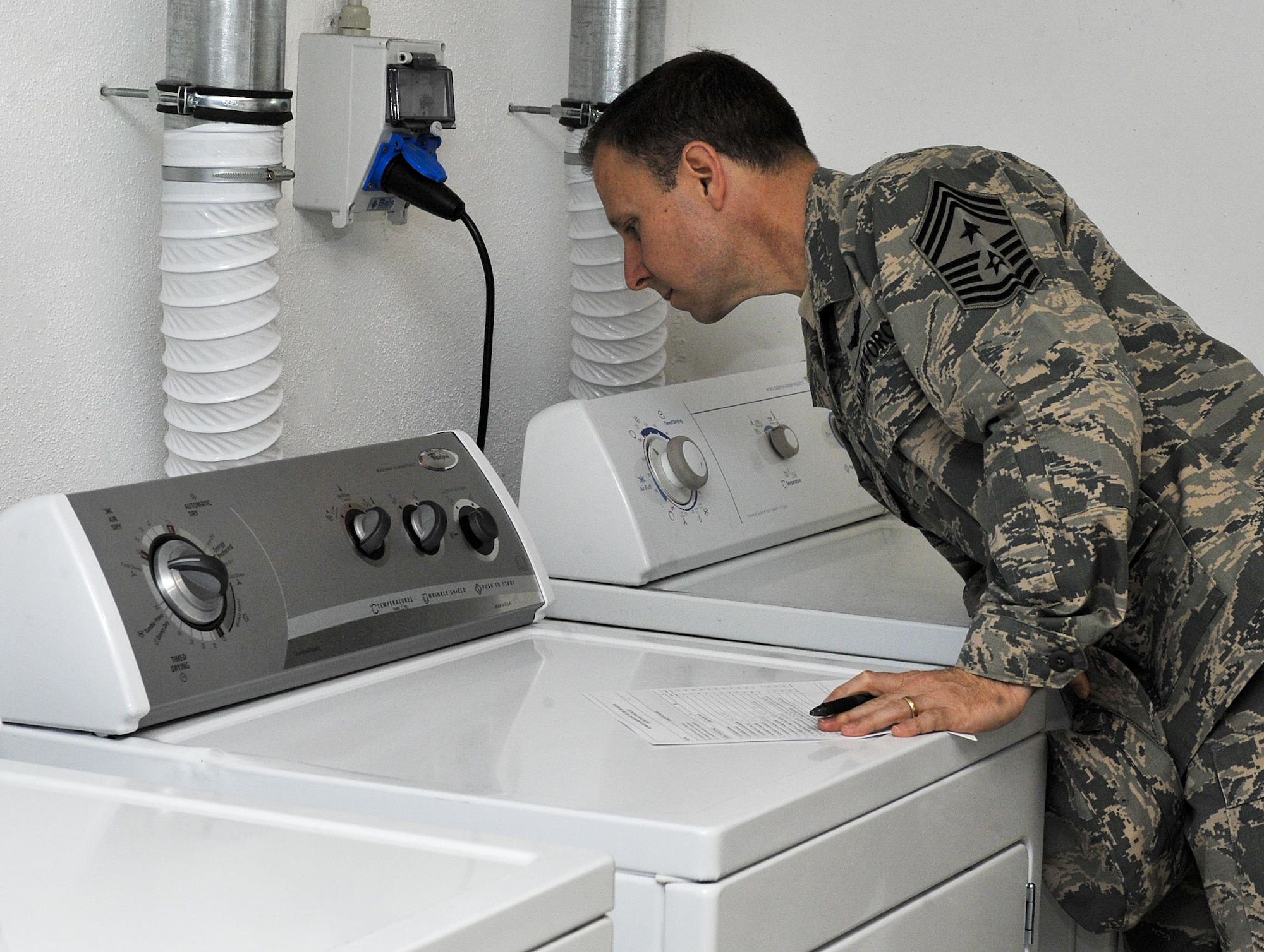 Chief Master Sgt. Mark Redden, 521st Air Mobility Operations Wing command chief, inspects a laundry room May 17, 2016, at Ramstein Air Base, Germany. For Ramstein’s first dorm of the quarter award, the first place dorm building received a $1,000 budget and the second place winners earned $500 to go toward whatever the residents agree upon to maintain or better their living quarters. (U.S. Air Force photo/Senior Airman Larissa Greatwood)
