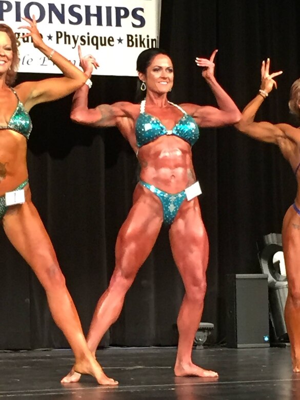 Staff Sgt. Annemarie E. Baker strikes a pose in the women’s physique competition during the 2016 National Physique Committee Gran Prix Natural competition in Rockford, Ill., May 14, 2016. Women like Baker have proven bodybuilding competitions no longer belong to men as more women, and especially mothers, have started competing.