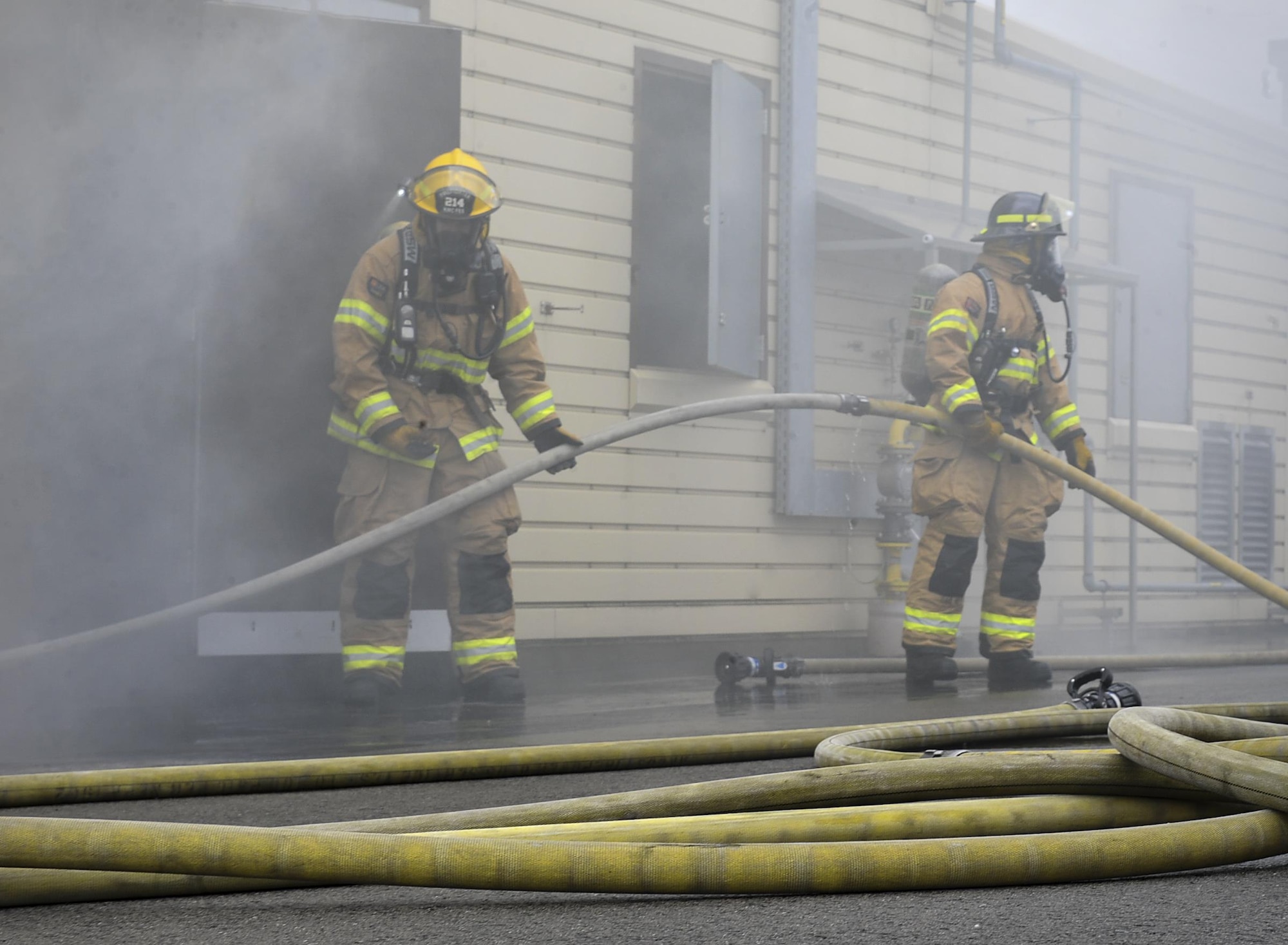 Airmen from the 86th Civil Engineer Squadron guide a firehose into a simulated burning house during a biannual training exercise June 2, 2016, at Ramstein Air Base, Germany. The Airmen constantly train for competency in their skillsets as well as expanding their training and knowledge. (U.S. Air Force photo/Senior Airman Larissa Greatwood)