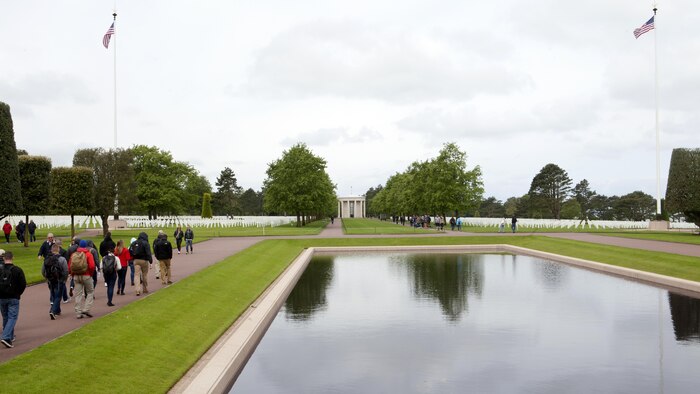 Marines from Headquarters and Service Battalion, Headquarters Marine Corps, Henderson Hall walk toward the graves of World War II service members interred at the Normandy American Cemetery in Colleville sur Mer, France, May 25, 2016. More than 70 Marines traveled to France for a professional military education trip to learn about military history.