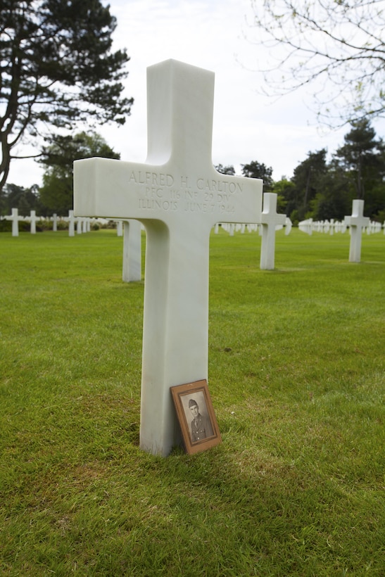 The photo of Army Pfc. Alfred H. Carlton rests against his headstone in the Normandy American Cemetery in Colleville sur Mer, France, May 25, 2016. Cpl. Joshua Bettis, an outbound clerk at distribution management office, Henderson Hall, was the first person in his family to visit this grave of his great, great uncle.  