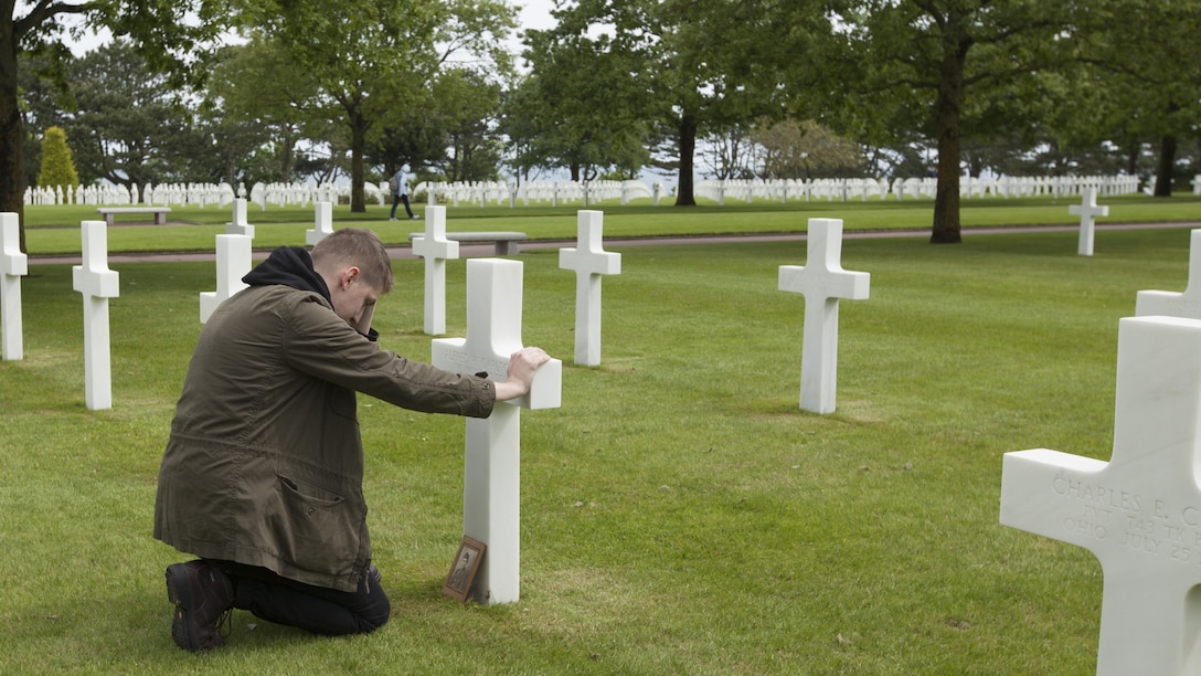 Cpl. Joshua Bettis, an outbound clerk at distribution management office, Henderson Hall, kneels at the grave of his great-great-uncle Army Pfc. Alfred H. Carlton at the Normandy American Cemetery in Colleville sur Mer, France, May 25, 2016. Carlton died from wounds in the D-Day invasion during World War II in Normandy, France. Bettis was the first person in his family to visit the gravesite. 