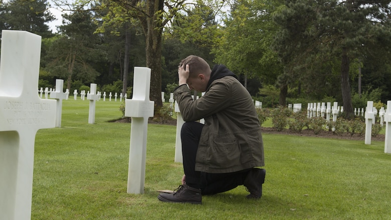 Cpl. Joshua Bettis, an outbound clerk at distribution management office, Henderson Hall, kneels at the grave of his great-great-uncle Army Pfc. Alfred H. Carlton at the Normandy American Cemetery in Colleville sur Mer, France, May 25, 2016. Carlton died from wounds in the D-Day invasion during World War II in Normandy, France. Bettis was the first person in his family to visit the gravesite. 