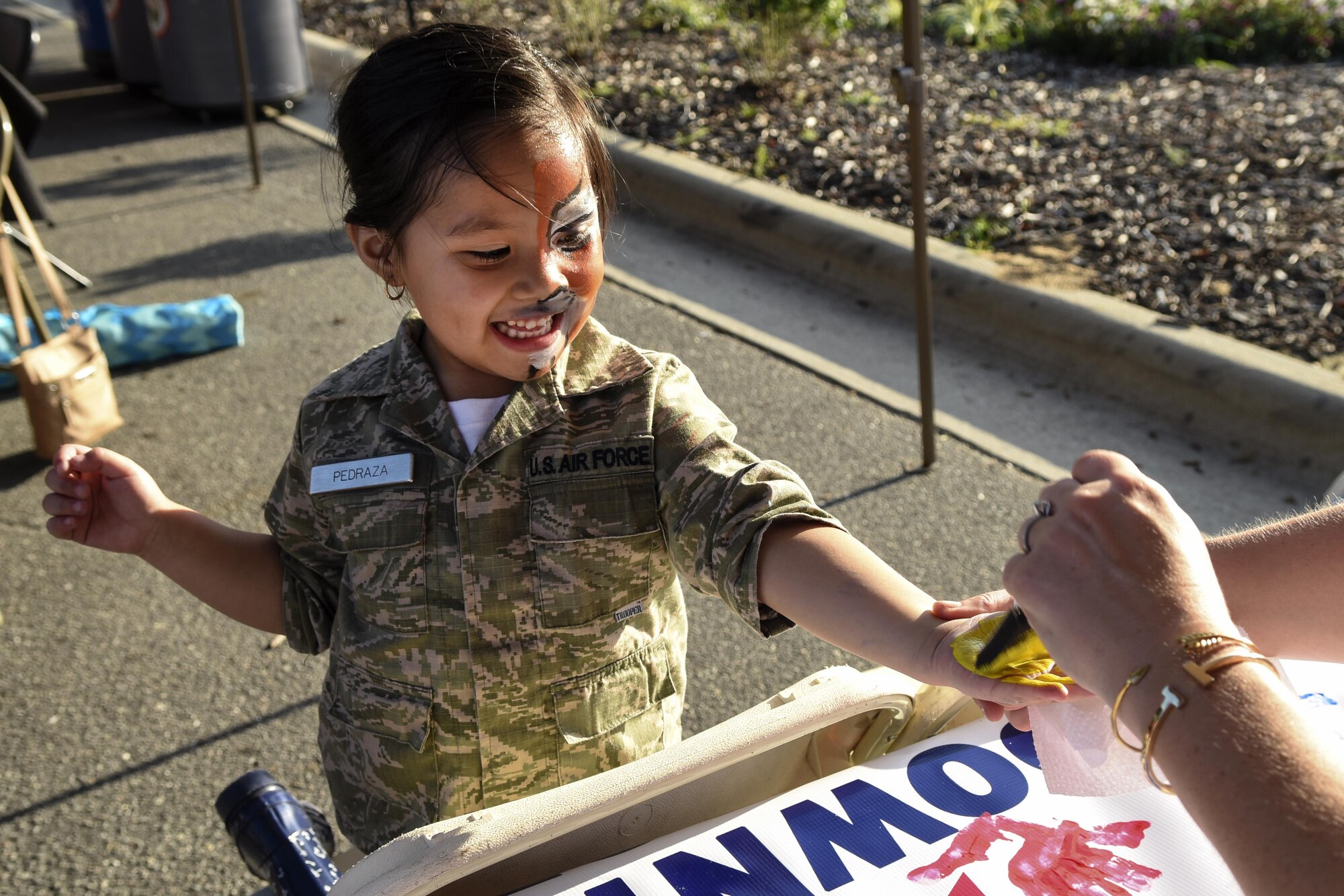The child of Senior Airman Juan Pedraza, 4th Fighter Wing command post emergency actions controller, interacts with a vendor during a military appreciation event, June 2, 2016, in Goldsboro, North Carolina. Children of both the local and base communities were encouraged to have their hands painted and placed on the banner that reads “Downtown Goldsboro supports military families.” (U.S. Air Force photo by Airman Shawna L. Keyes/Released) 