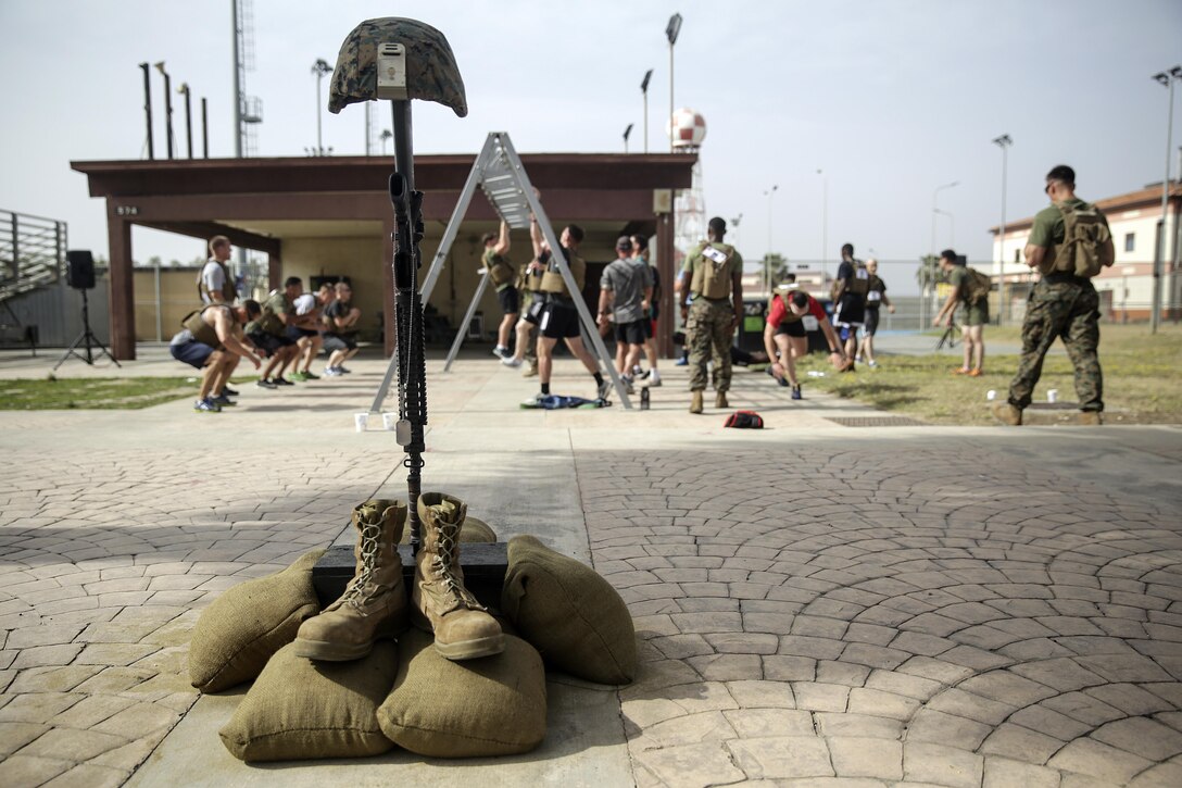A tribute memorial to fallen service members stands by the pull up bars as Marines with Special Purpose Marine Air-Ground Task Force Crisis Response-Africa complete the Memorial Day Murph challenge at Naval Air Station Sigonella, Italy, May 30, 2016.  Marines and sailors ran one mile, completed 100 pull-ups, 200 push-ups, 300 air squats and another 1-mile run, all while wearing a flak jacket.  (U.S. Marine Corps photo by Cpl. Alexander Mitchell/released)