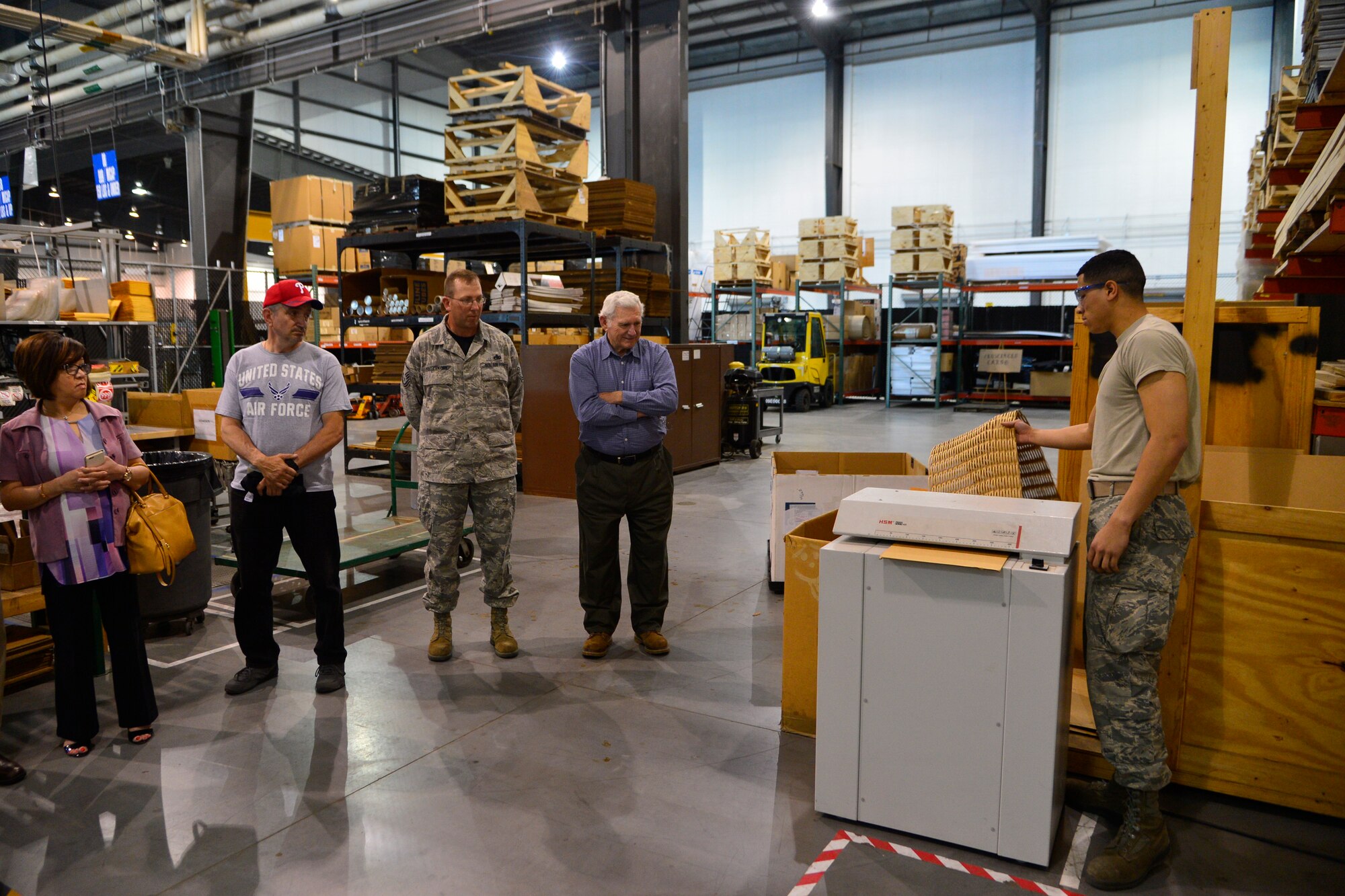 Airman Alejandro Catalan, 436th Aerial Port Squadron packing and crating specialist, demonstrates how the aerial port uses scrap cardboard and converts it to packing material during 436th APS 50th Anniversary Celebration May 20, 2016, inside of the aerial port on Dover Air Force Base, Del. Former port dawgs were given a tour of the aerial port to see how the Super Port has evolved over the past 50 years. (U.S. Air Force photo/Senior Airman William Johnson)