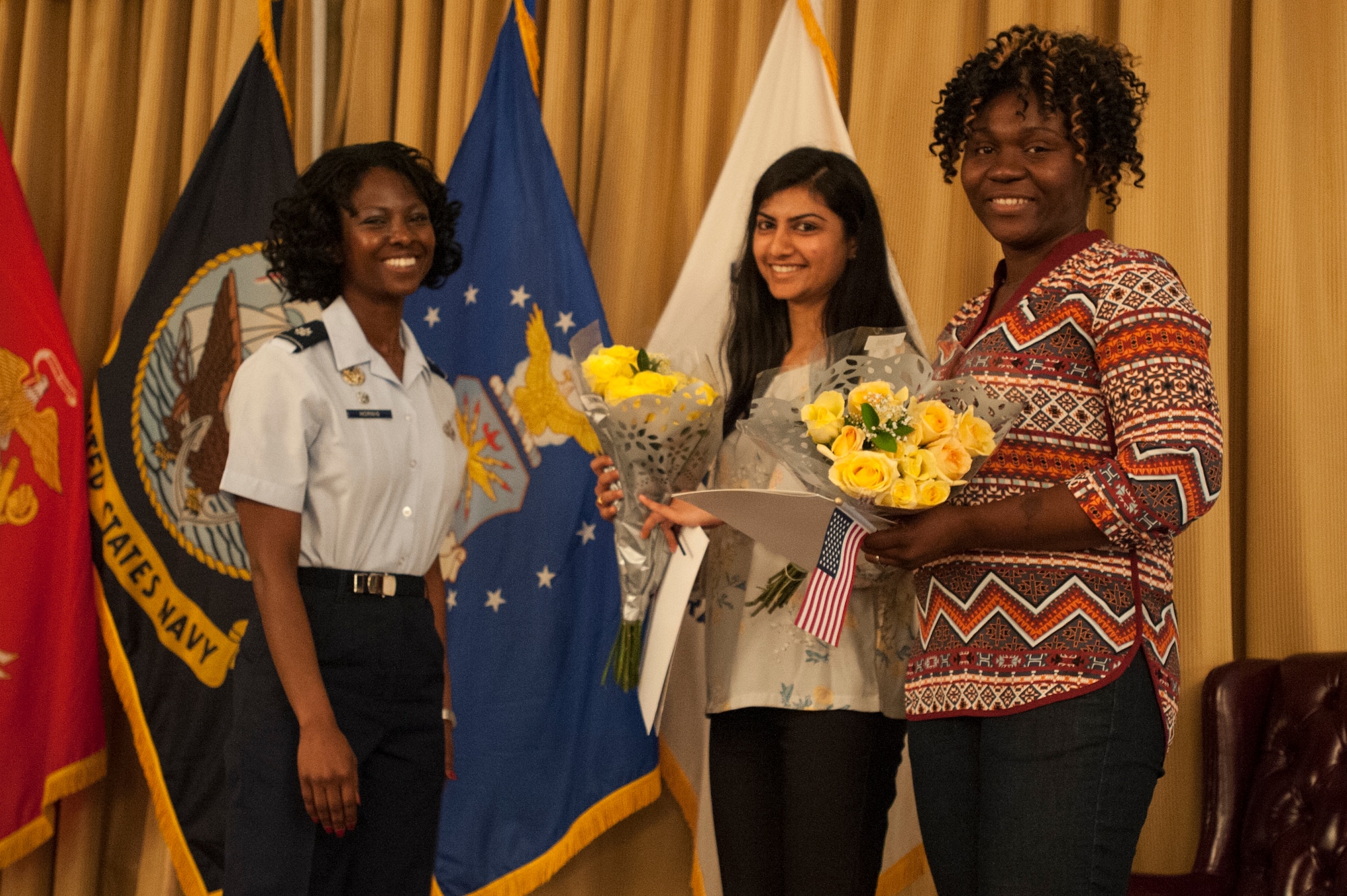 Lt. Col. Charlotta Hornig, 87th Force Support Squadron commander, presents flowers to military spouses Roma Patel and Justina Moses to congratulate them on earning their US citizenship at the Spouse Appreciation Luncheon at Tommy B’s Community Center at Joint Base McGuire-Dix-Lakehurst, June 1, 2016. The Spouse Appreciation Luncheon is held annually and recognizes the achievements of military spouses.(U.S. Air Force photo by Airman 1st Class Zachary Martyn/released)