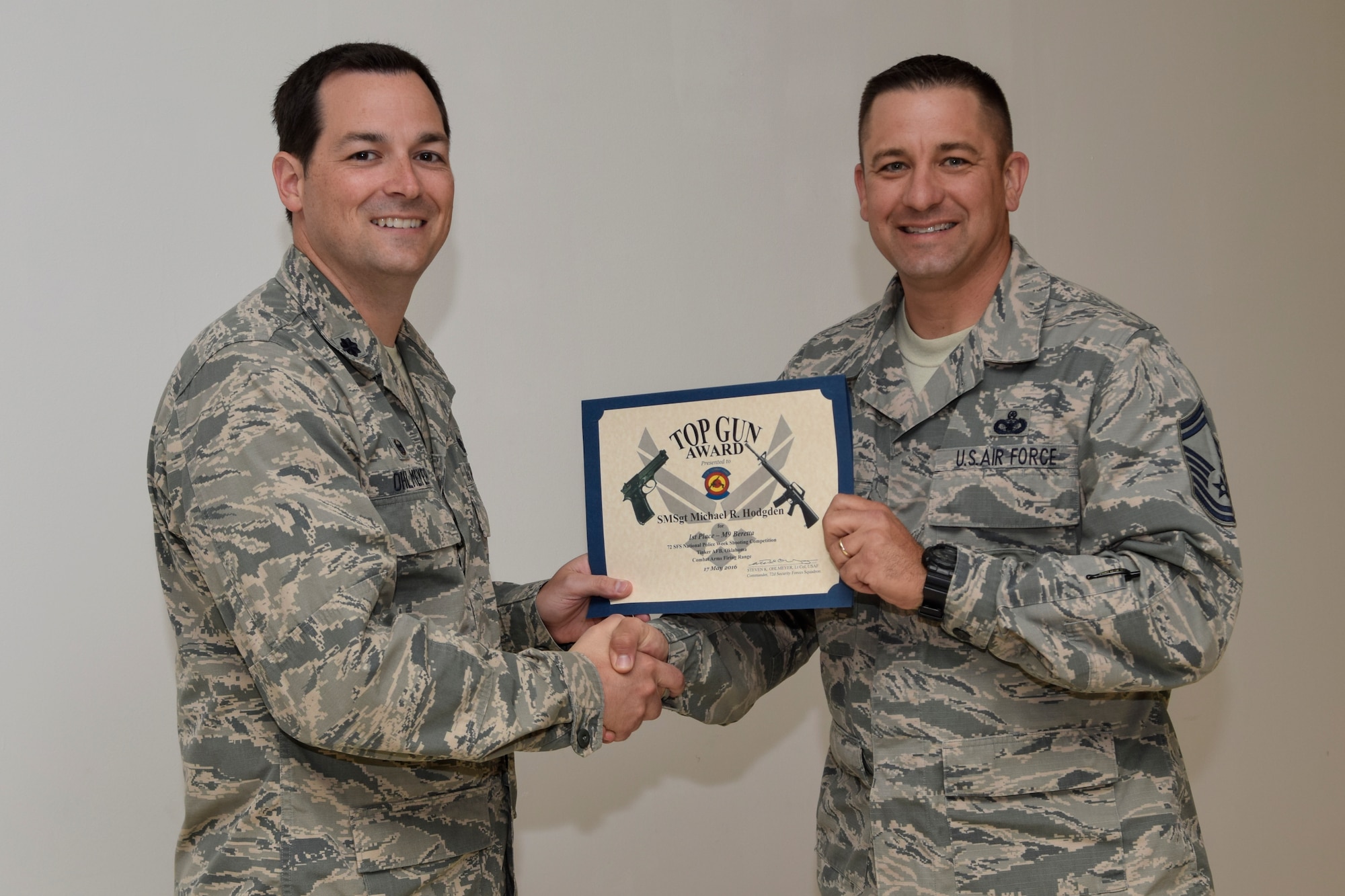 Lt. Col. Steven Ohlmeyer, 72nd Security Forces Squadron commander, presents the 'Top Gun Award' for best individual shooting score to Senior Master Sgt. Michael Hodgden, 72nd SFS operations superintendent, following a pistol competition held during Police Week 2016 on Tuesday May 17, 2016, Tinker Air Force Base, Okla. Teams of shooters from multiple units assigned to the base competed in the event which challenged shooters in both speed and accuracy events. (U.S. Air Force photo/Greg L. Davis)
