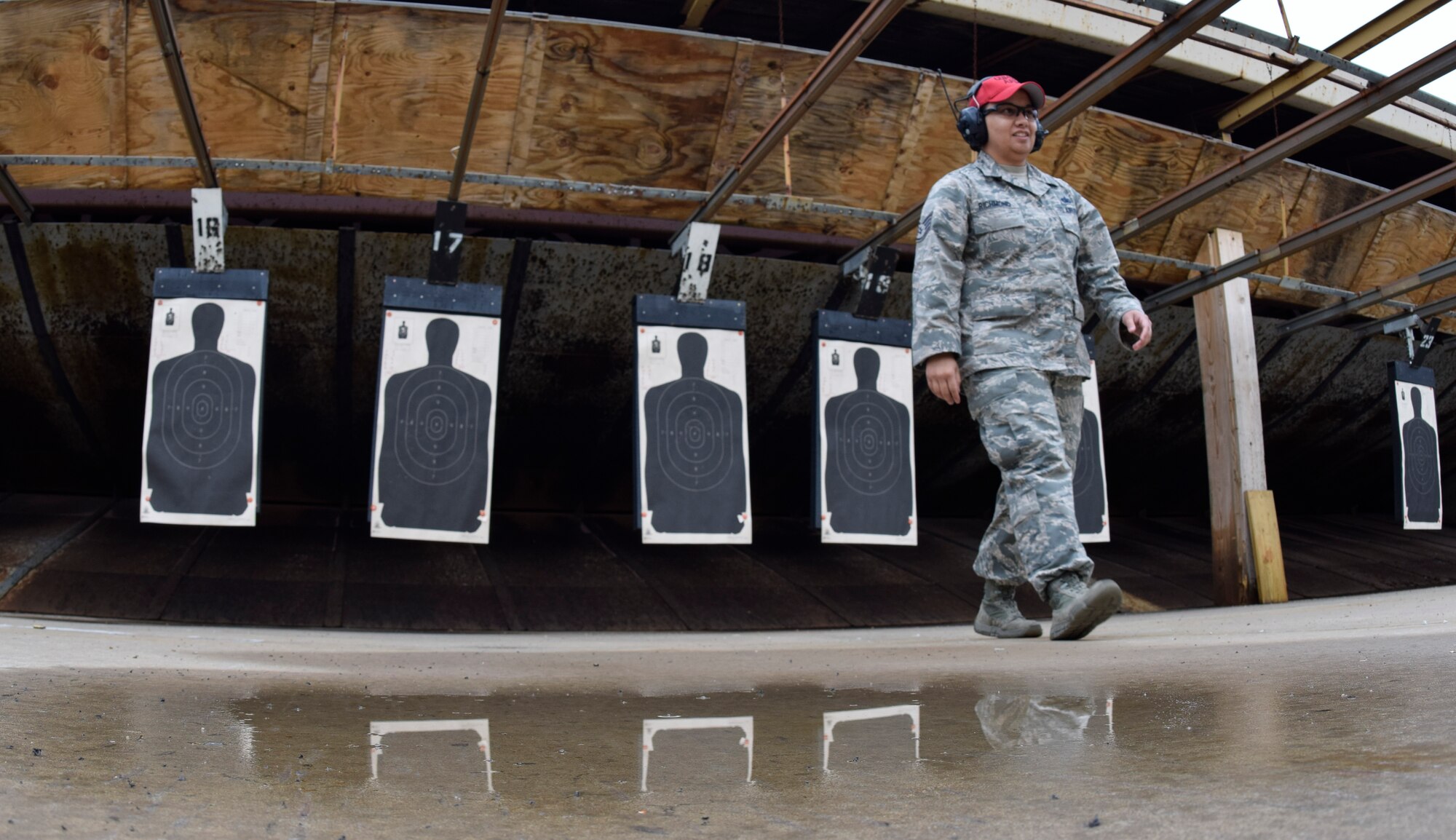 Staff Sgt. Joanna Richmond, 72nd Security Forces Squadron combat arms instructor, walks away from target silhouettes she has just scored during the 72nd Security Forces Squadron pistol competition held in conjunction with Police Week 2016 activities on Tuesday May 17, 2016, Tinker Air Force Base, Okla. The scene is partially reflected in a pool of water from rain storms the previous night.  (U.S. Air Force photo/Greg L. Davis)