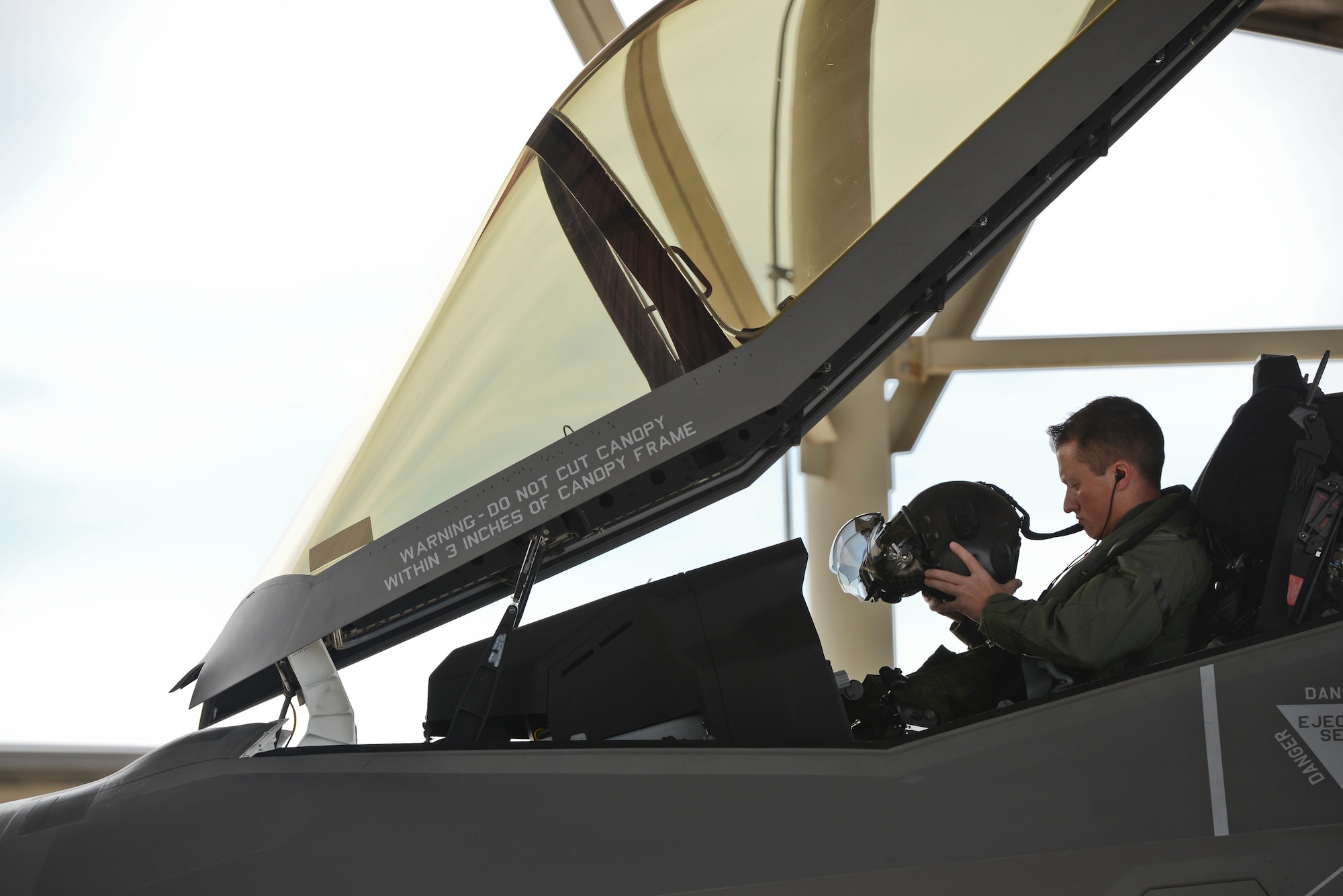 Capt. Derek Kirkwood, a pilot assigned to the 34th Fighter Squadron, dons his helmet in the cockpit of an F35A Lightning II aircraft April 22 at Hill Air Force Base, Utah. The sortie, the first F-35A 4-ship generation at the base, was part of a cross-ramp exercise and was a major test for the active duty 388th Fighter Wing and Reserve 419th Fighter Wing. The exercise helped identify process deficiencies before testing the F-35's operational agility at Mountain Home AFB, Idaho, in June. (U.S. Air Force photo by Paul Holcomb)