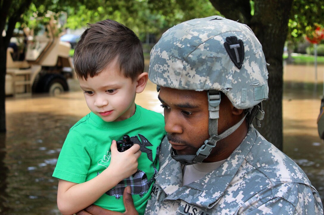A soldier carries a young boy through deep water to load him into a vehicle during severe flooding in Rosenberg, Texas, June 2, 2016. Texas Army National Guard soldiers are supporting local first responders with search and rescue operations following flash flooding in the region. Army photo by Will Welch