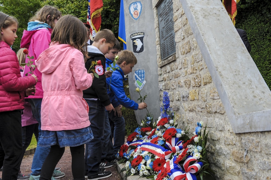 French children place flowers at the Currahee Memorial in Beuzeville au Plain, France.