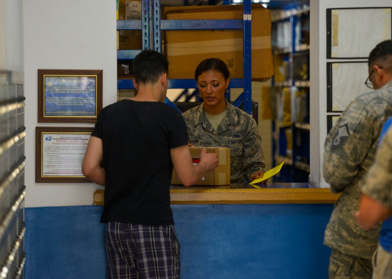 Airman Tazesha Wilson, 51st Communications Squadron postal clerk, delivers a package to a customer at Osan Air Base, Republic of Korea, June 3, 2016. The postal clerks verify the identities of customers before providing them with inbound packages. (U.S. Air Force photo by Senior Airman Victor J. Caputo/Released)