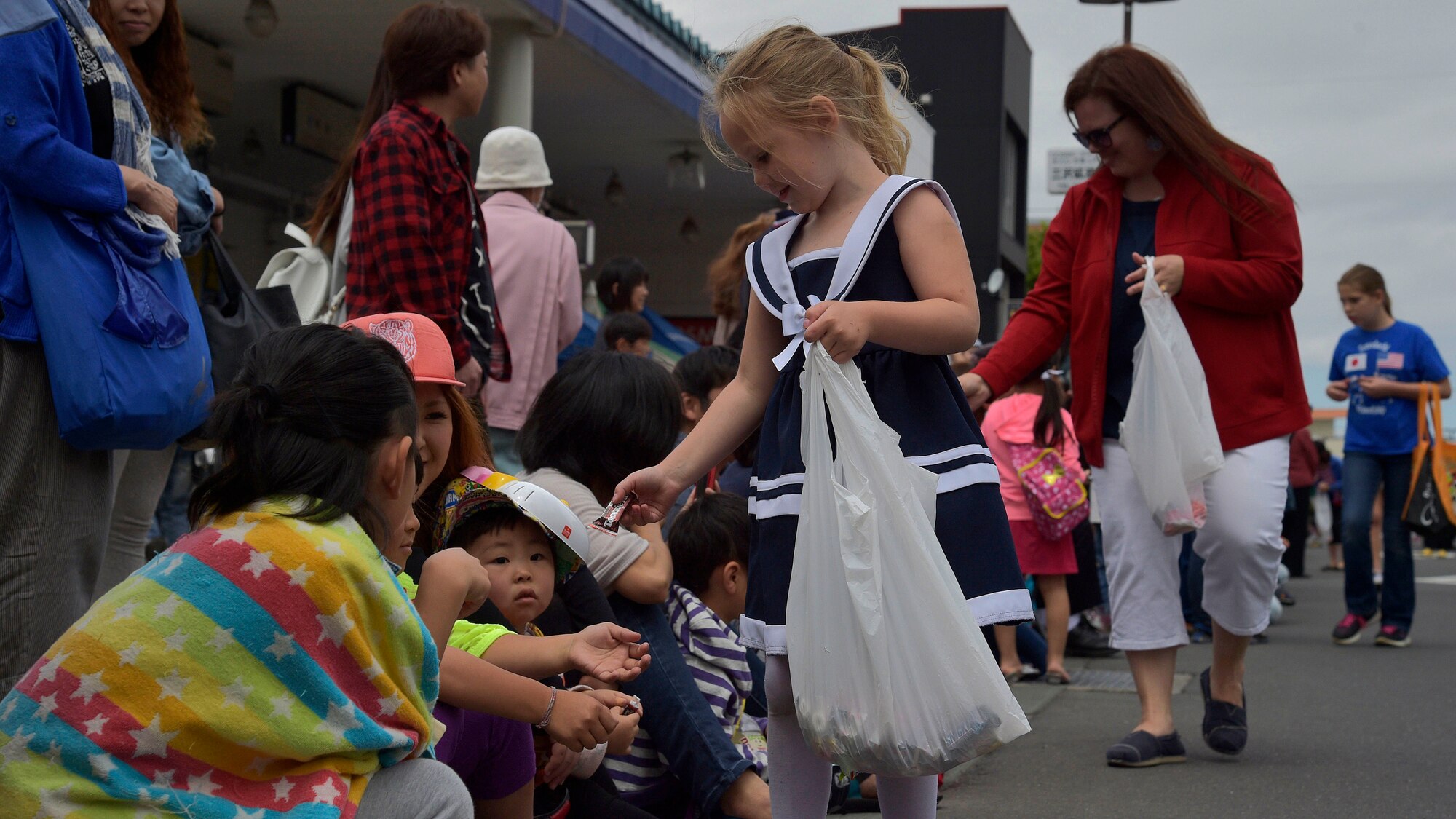 Team Misawa families pass out candy to a local Japanese family during the 28th Annual American Day parade in Misawa City, Japan, June 5, 2016. Events like these are important as they afford Misawa neighbors, American and Japanese alike, opportunities to interact in a relaxed environment specifically planned for building friendships. More than 80,000 attendees enjoyed live performances, including Sublime with Rome, indulge in American and Japanese cuisine and to strengthen international bonds. (U.S. Air Force photo by Senior Airman Deana Heitzman)