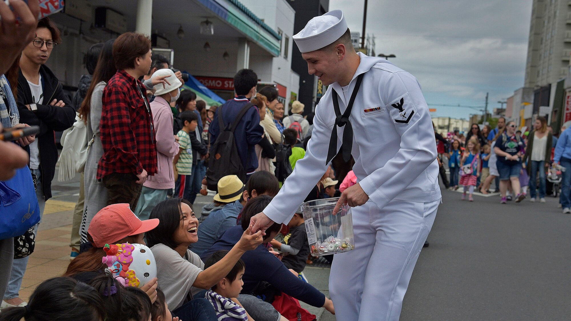 A U.S. Navy Sailor with the Naval Air Facility-Misawa hands out candy to a Japanese family during the 28th Annual American Day parade in Misawa City, Japan, June 5, 2016. Events like these are important as they afford Misawa neighbors, American and Japanese alike, opportunities to interact in a relaxed environment specifically planned for building friendships. More than 80,000 attendees from across the Aomori Prefecture traveled to Misawa City to enjoy American and Japanese culture. (U.S. Air Force photo by Senior Airman Deana Heitzman)