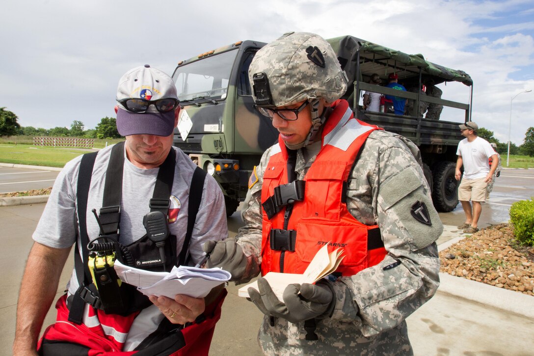 A soldier and a Texas first responder discuss a safe route after picking up stranded residents during severe flooding in Rosenberg, Texas, June 3, 2016. Texas Army National Guard photo by Staff Sgt. Timothy Pruitt