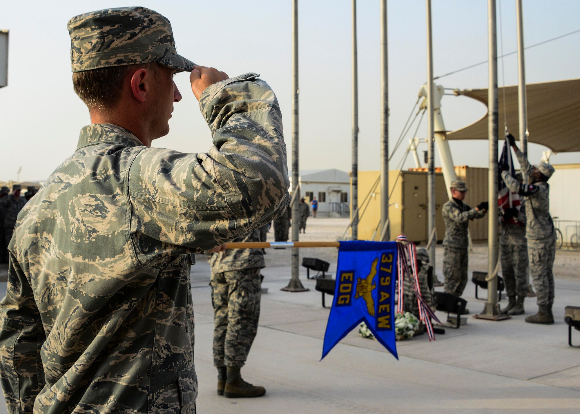 Lt. Col. Timothy Hofman, 7th Expeditionary Airborne Command and Control Squadron commander, salutes as base honor guard members lower the American flag during a Memorial Day ceremony May 30, 2016, at Al Udeid Air Base, Qatar. Memorial Day, which is observed the last Monday of May, was initiated to honor the soldiers from the Union and Confederate armies who died during the American Civil War. (U.S. Air Force photo/Senior Airman Janelle Patiño/Released)