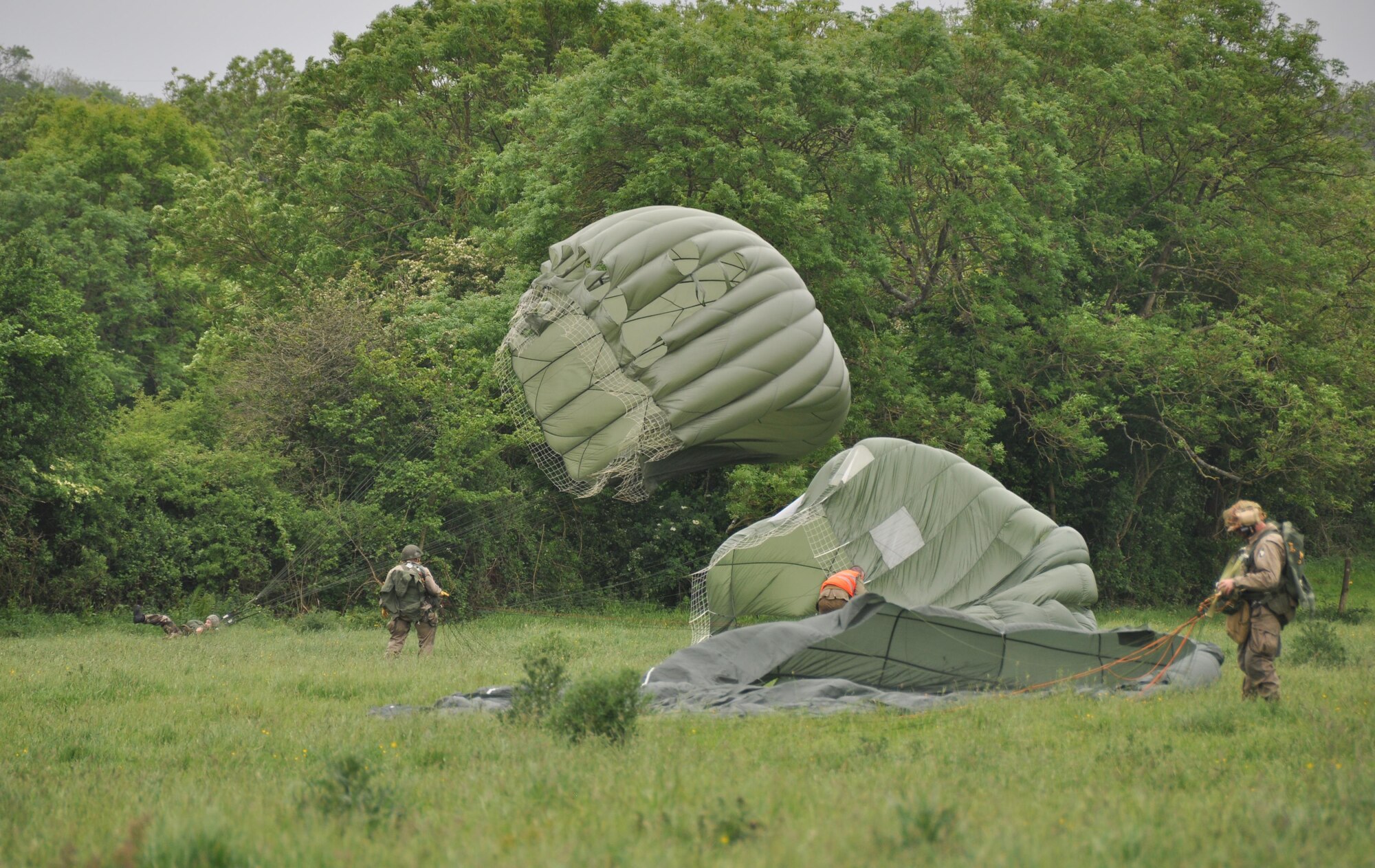 Members of the Round Canopy Parachuting Team, dressed in D-Day period costumes, parachuted into Fresville, France June 2, 2016 during an exhibition jump.  The Round Canopy Parachuting Team invited members of the 815th Airlift Squadron to assist in the drop zone.  More than 380 service members from Europe and affiliated D-Day historical units are participating in the 72nd anniversary as a part of Joint Task Force D-Day 72.  The Task Force, based in Sainte-Mère-Église, France, is supporting local events across Normandy, from May 30 - 6 June, 2016 to commemorate the selfless actions by all of the allies on D-Day that continue to resonate 72 years later.  (U.S. Air Force photo by Master Sgt. Jessica L. Kendziorek)
