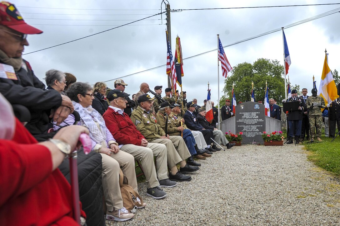 U.S. Army Col. Al Boyer, second from right, commander of the 101st Airborne Division’s 1st Brigade Combat Team, speaks about the actions and humanity displayed by U.S. Army veterans Kenneth Moore and Robert Wright during World War II at a memorial ceremony in Angoville au Plain, France, June 4, 2016. Air Force photo by Staff Sgt. Timothy Moore