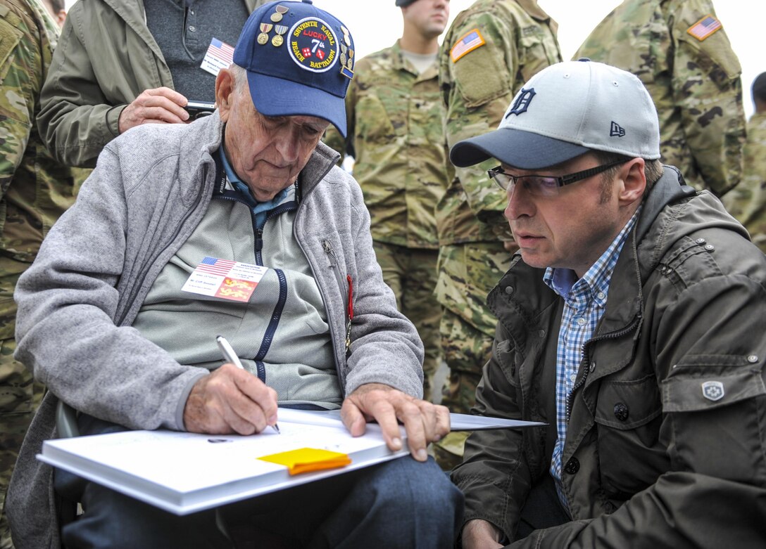 Cliff Goodall, a World War II veteran, signs an autograph after a memorial ceremony in Angoville au Plain, France, June 4, 2016. Air Force photo by Staff Sgt. Timothy Moore