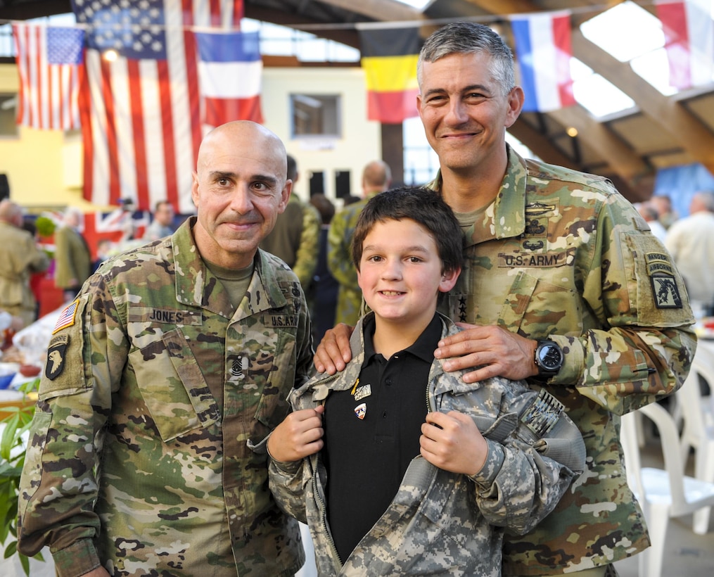 U.S. Army Lt. Gen. Stephen J. Townsend, right, commanding general of the 18th Airborne Corps, and U.S. Army Command Sgt. Maj. Benjamin Jones, left, assigned to the 18th Airborne Corps, pose for a photograph with a French child during the Liberty Banquet in Sainte Mere Eglise, France, June 4, 2016. Air Force photo by Staff Sgt. Timothy Moore